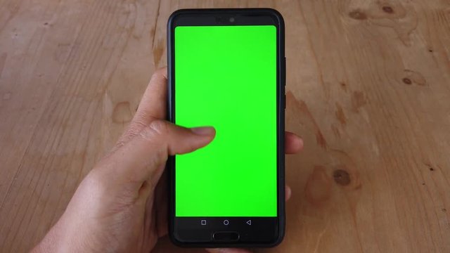 One hand using a smart phone with green screen on display 