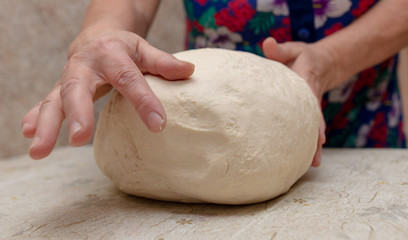 Woman kneads dough with hands in the kitchen