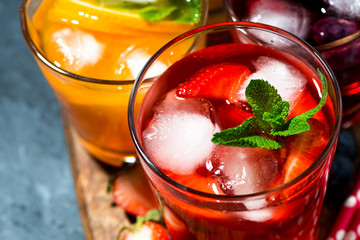 cold fruit and berry beverages in assortment on dark table, top view closeup