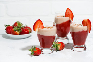 sweet strawberry yoghurt milkshake in glasses on white wooden table