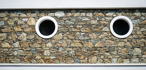 stone wall with two porthole-shaped windows