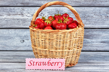 Wicker basket full of fresh strawberries. Fragrant ripe strawberries in basket on vintage wooden...