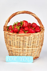 Fototapeta na wymiar Wicker basket with garden strawberries. Romantic composition from strawberries on white background.