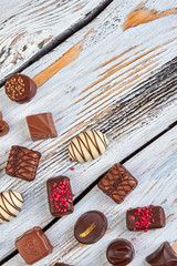 Assorted chocolate candies, top view. Delicious chocolate candies on vintage wooden surface and copy space.