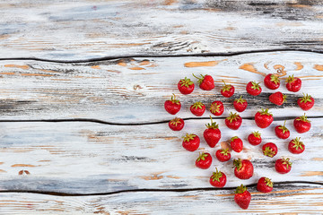 Strawberries in a shape of heart on wooden background. Heart shape made of sweet berries and copy space. Taste of summer love.