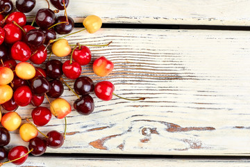 Naklejka na ściany i meble Mix of ripe cherries and copy space. Healthy delicious berries on old wooden boards. Reasons to eat fruits.