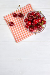 Naklejka na ściany i meble Ripe juicy cherries in bowl, top view. Healthy summer berries on white wooden surface with copy space. Summer fruits refreshment.
