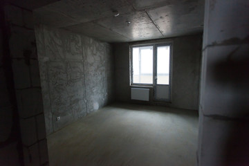 Unfinished building interior, gray room. Repairs in the apartment. Preparing in the room.