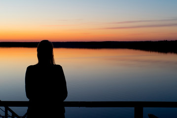 Young woman at sunset near lake silhouette