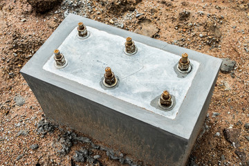 Concrete footing supporting steel beam building under construction. Welded base plate and connecting,steel plate on concrete floor.