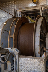 Wireline equipment hanging from top drive ready to be lowered downhole for logging. An oil well engineer works from the back of specialised van to log the condition of steel casing inside an oil well