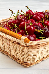 Ripe healthy cherries in wicker basket. Delicious summer berries with water drops. Summer fruits refreshment.