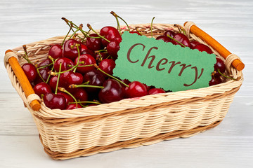 Fresh sweet cherries in wicker basket. Ripe natural berries on white wooden background. Tasty harvest from garden.