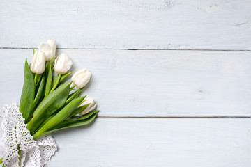 bunch of white tulips on blue wooden table. Banner mockup card with copy space for congratulation, woman or mother day, easter, spring holiday, birthday