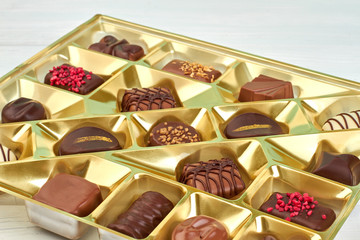 Collection of chocolate candies in golden box. Candies in opened box close up. Sweet gift on Birthday.