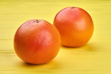 Ripe juicy grapefruits on light background. Fresh delicious grapefruits on yellow wood. Grapefruit health benefits.