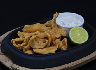 deep fried anchovies with tartar sauce and lime wedge in a serving dish