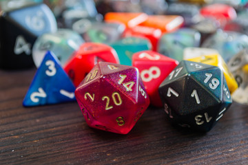various colorful polyhedral game dice on a table with a 20 and a one in the foreground