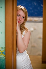 Fototapeta premium Young blonde woman in white dress staying indoors in room