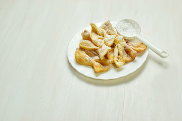 a plate full of angel wings sprinkled with powdered sugar