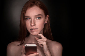 The portrait of a young redhead lady isolated over a black background