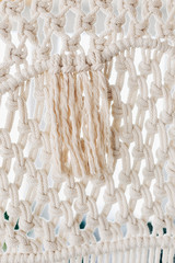 Detail of cream macrame decor displayed hanging on a wall.