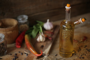 Close-up. olive oil in a bottle on a wooden background with a wooden board with garlic, spices, dried pepper and herbs for decoration