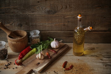 still life with olive oil and spices chili pepper, garlic, parsley on a wooden rustic background. With copy space for text.