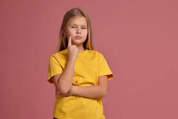 little girl in a yellow t-shirt. thoughtfully shows finger