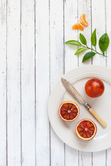 Fresh blood orange fruits on white plate with knife