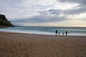 Silhouettes of the family who walks on the Mediterranean Sea coast in winter.  Off season February. Winter tourism in Provence.