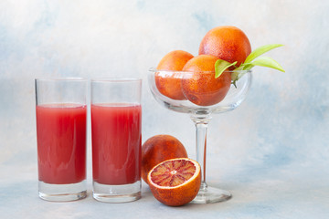 Close-up of Two glasses of cold fresh blood orange  juice and blood oranges.