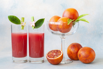 Close-up of Two glasses of cold fresh blood orange  juice and blood oranges.
