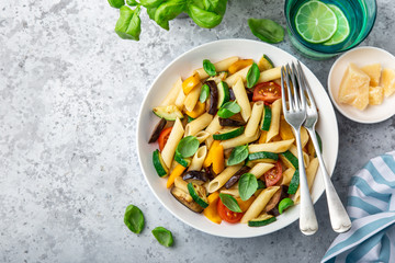 pasta with grilled vegetables ( zucchini, eggplant, bell pepper ant tomato) in white bowl