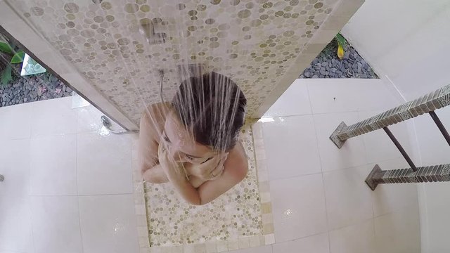 Young sexy girl taking a rain shower in a Villa or hotel. Naked long red hair woman washes.