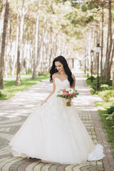 Beautiful bride in a white wedding dress on outdoors. Holding a wedding bouquet