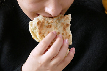 a young girl eats bread in her hand,