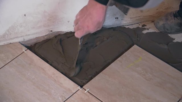 A tiler mixes the cement mortar and lays the tile
