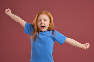 Portrait of cute redhead emotional little girl on red background