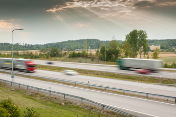 Blurred cars in motion. Asphalt road with cars at autumn beautiful sunset in Finland.