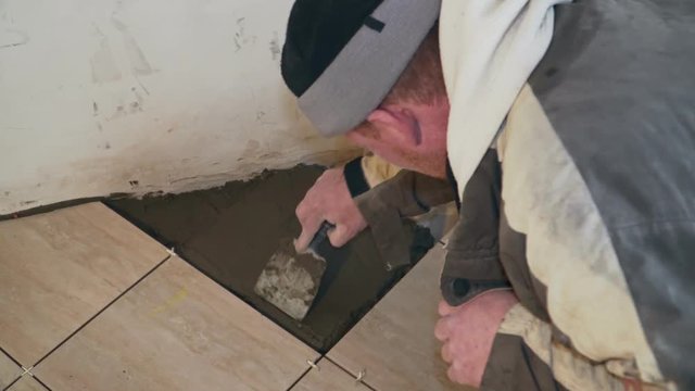 The tiler mixes a cement mortar and lays the tile