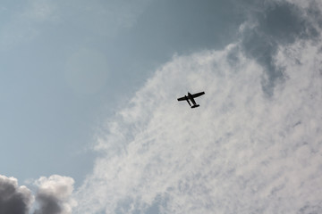 Airplane silhouette at blue sky and clouds background.