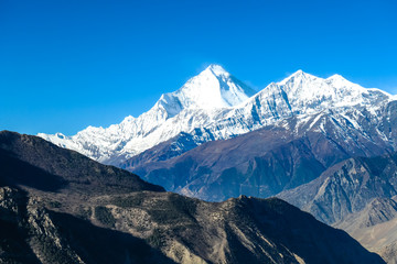 Harsh slopes of Manang Valley, Annapurna Circus Trek, Himalayas, Nepal, with the view on Annapurna Chain and Gangapurna. Dry and desolated landscape.  High mountain peaks, covered with snow.