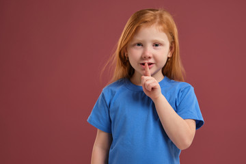 Portrait of cute redhead emotional little girl on red background