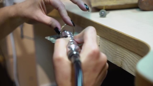 Jeweler makes a piece of jewelry - golden wedding ring