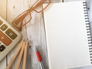 Notebook, pen, calculator, glasses, office equipment on a vintage white wooden background