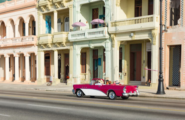 Amerikanischer rot weisser Cabriolet Oldtimer fährt auf dem berühmten Malecon an der Häuserfront entlang in Havanna Kuba - Serie Kuba Reportage