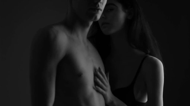 A man with a girl in the studio on a gray background. Black and white video.