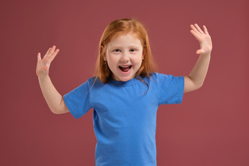 Portrait of cute redhead emotional little girl on red background