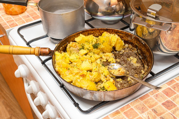 Fried potatoes with dill in a pan on gas stove